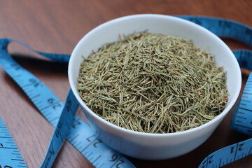 Rosemary or Salvia rosmarinus, dry leaves in white bowl, herb and seasoning