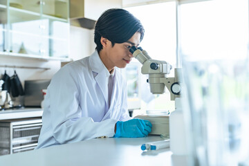 Naklejka premium 顕微鏡で観察する男性 科学者