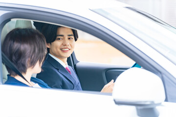 女性に運転を指導する男性　自動車教習所　試乗車　カーディーラー
