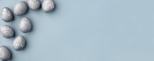 Festive Easter background. Gray-blue Easter eggs with stars on a blue table. Banner with a place for text. Top view.