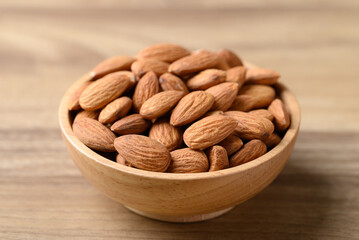 Raw almond nut in bowl on wooden background