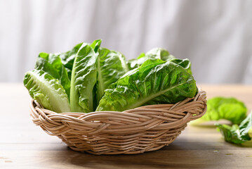 Organic cos romaine lettuce in basket on wooden table, Food ingredient for healthy salad - obrazy, fototapety, plakaty