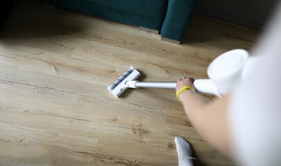 Female hand vacuums floor covering in an apartment. Purchase powerful model with smooth power...