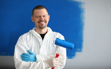 Male painter in uniform with roller in his hand. Limitations person with an allergy to use paint. Walls made concrete or structural gypsum. Perfectly painted walls apartment and impeccable structure