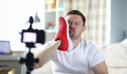 Man takes photo with sneaker face, front camera. Video blogger demonstrates appearance product and...