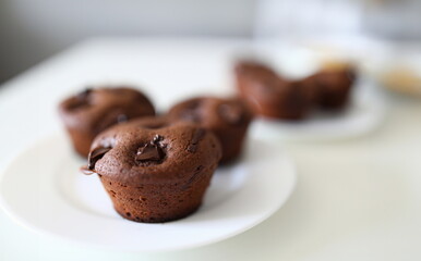Close up, on white plate are chocolate muffins. On the table is plate and natural homemade cakes. Training on confectioner on their own during quarantine. Gluten free flour, organic dessert