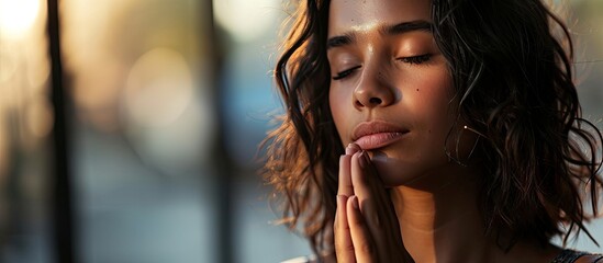 One young hispanic black woman in joining hands in prayer Meditative Brazilian adult girl praying in contemplation with eyes closed. Copy space image. Place for adding text or design - Powered by Adobe