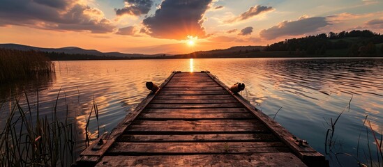 landscape of a lake at sunset and with a wooden jetty. Copy space image. Place for adding text or design