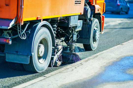 Asphalt brush of a sweeper cleaning roads in the city. Municipal street cleaning service.