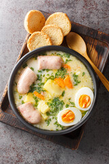 Polish soup zurek with white sausage and eggs close-up in a bowl on the table. Vertical top view...