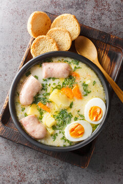 Polish soup zurek with white sausage and eggs close-up in a bowl on the table. Vertical top view from above