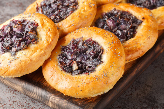 Cebularz Lubelski is a round-shaped Polish Onion poppy flatbread close-up on a wooden board on the table. Horizontal