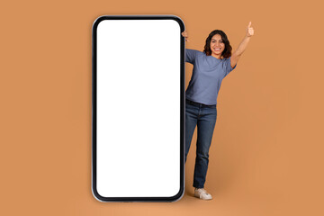 Middle eastern woman stand by big phone with blank screen