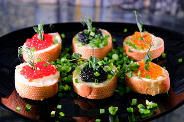 Partitioned dish with black and red caviar on wooden background