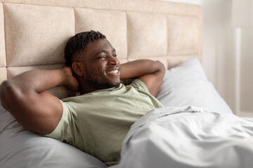 African Man Lying Awake In Bed Holding Hands Behind Head