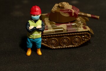 Fototapeta premium miniature worker with a war military tank
