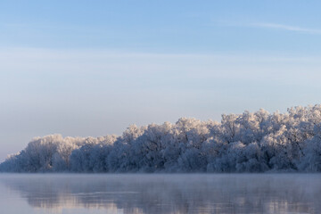 A winter tableau unfolds along the river’s edge. Nature’s brush has painted a serene masterpiece — the water