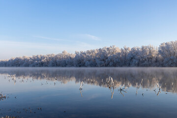 A winter tableau unfolds along the river’s edge. Nature’s brush has painted a serene masterpiece — the water