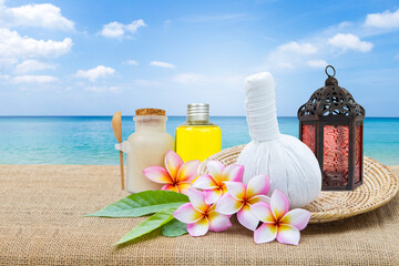 Herbal massage ball with scrub set and arabian lanter on wooden tray with space on beautiful tropical beach, spa treatment, summer outdoor day light