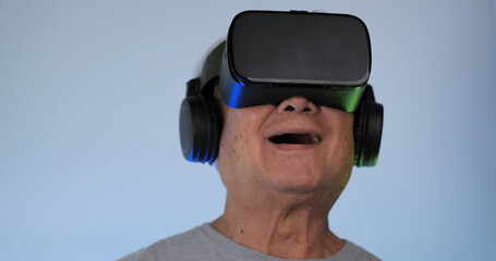 Asian old man having fun playing games while wearing virtual reality glasses.