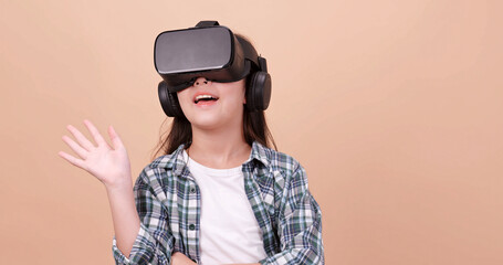 A girl having fun with game while wearing virtual reality glasses. Isolated on brown background in studio.