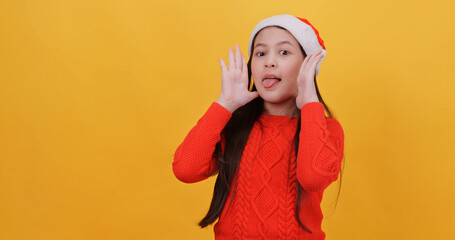 Cute little girl wearing a Christmas dress. Isolated on yellow background in studio.