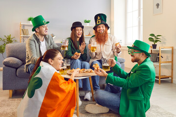 Company of friends celebrating Saint Patrick Day at home. Dressed in green attire adorned with...
