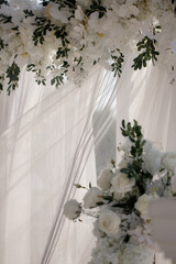 Elegant wedding arch with fresh flowers, vases against the backdrop of the ocean and blue sky.
