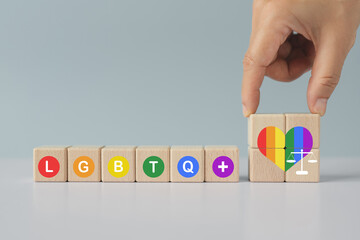 Concept of LGBTQ rights and law. pride month celebrate annual in June social of gay, lesbian, bisexual, transgender, human rights. Hand arranged wooden cube with text in multicolor circle and heart