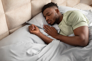 High angle of african american man lying asleep in bed