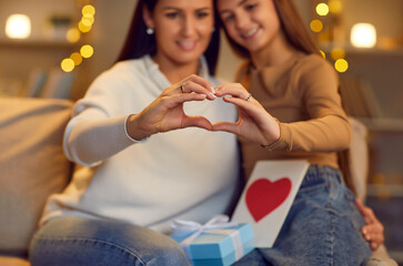 Obraz na płótnie Canvas Mini heart gesture mother and daughter, happy smiling family people in love. Parent, child sharing special close moment, Valentine day emotion, showing kind feelings, appreciation, holding card, gift