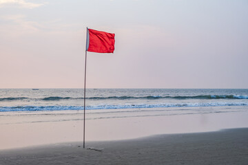 red flag on beach on sea or ocean as a symbol of danger. The sea state is considered dangerous and...