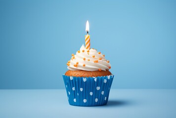 a white cupcake with blue polka dots with a blue candle on the background and a blue background