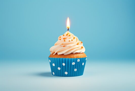 a white cupcake with blue polka dots with a blue candle on the background and a blue background