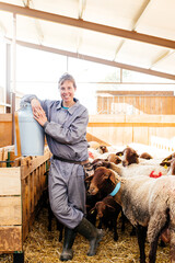 Smiling female farmer standing near sheep