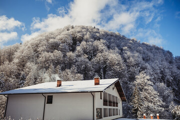 Winter landscape in the mountains with a roof and chimney house