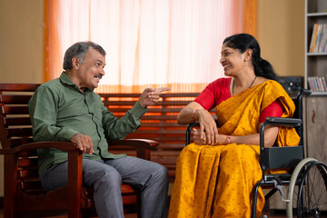 Happy husband with recovered injured wife on wheel chair spending time together at home - concept...