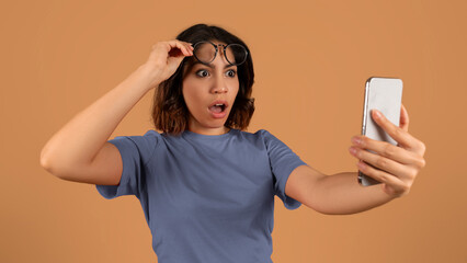 Shocked young arab woman looking at smartphone screen