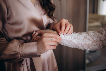 Bride and mothers hands helping put on wedding dress