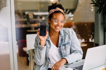Young woman smiling and recommending a mobile app on her phone