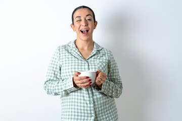 Beautiful young woman wearing green plaid pyjama winking looking at the camera with sexy...