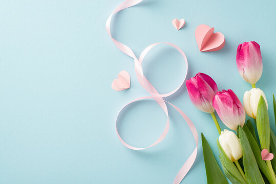 Express your love on Woman's Day with a top-view image showcasing fresh tulips, heart motifs, and an elegant 8-shaped silk ribbon—all set against a soft pastel blue background