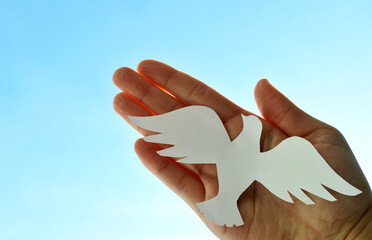 White paper origami bird on blue sky background. World Day of Peace. Day Against Humiliation....