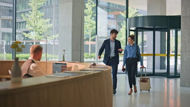 Business people check hotel on trip. Smiling receptionist at counter greeting
