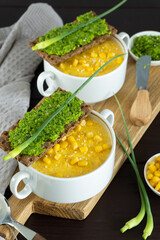 Corn soup with fresh garlic pate in bowl. Healthy food on black wooden background. Vegan cuisine
