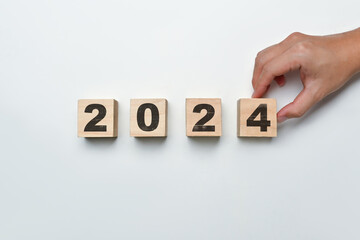 Starting to new year and business vision concept. Hand flipping wooden block cube to 2024