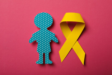 A paper figure of a child with a yellow ribbon