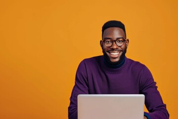 smiling man in eyeglasses and purple sweater using laptop on orange background, remote work