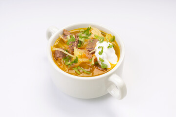 Traditional Russian cabbage and meat soup in a white bowl on a white background