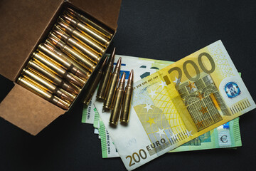 European money and rifle cartridges in 5.56x45mm NATO caliber. Close-up photo.